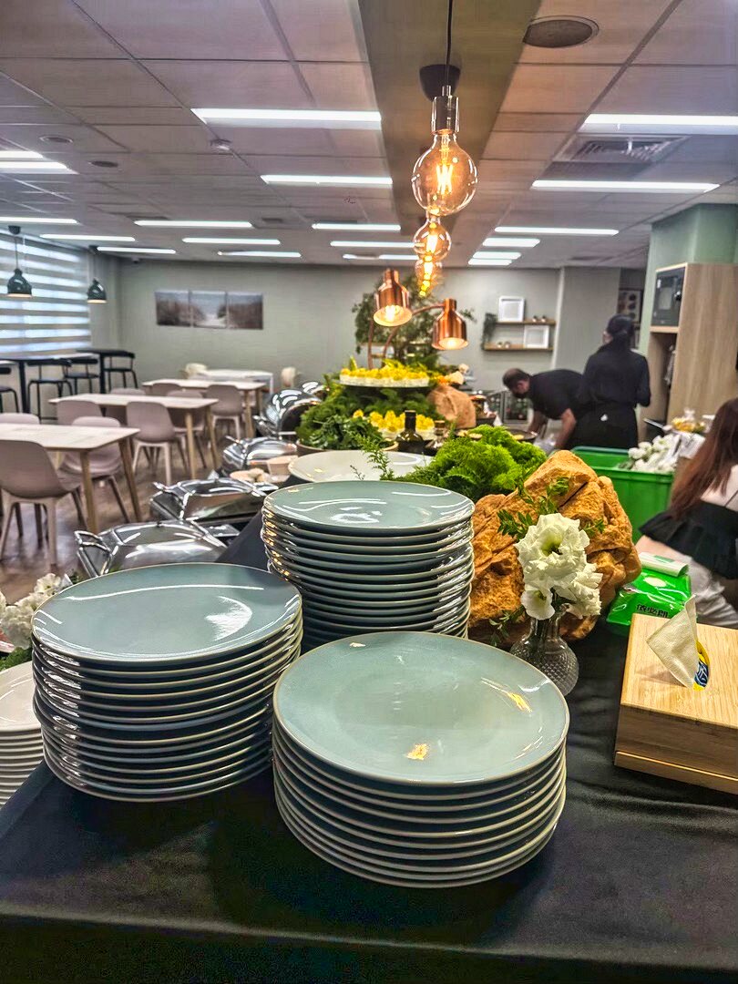 企業會議餐會外燴場地全景，現場備有自助餐檯、餐盤、植栽佈置與用餐座位